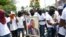 Miembros de una pandilla encabezada por Jimmy Cherizier, alias Berbecue, un expolicía que lidera una coalición de pandillas llamada "Familia G9 y Aliados", transportan un retrato del asesinado presidente Jovenel Moise durante una marcha efectuada el lunes 26 de julio de 2021.