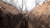 FILE - A Ukrainian serviceman walks in a trench on the frontline with Russia-backed separatists near town of Krasnogorivka, Donetsk region, April 23, 2021. 