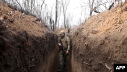 FILE - A Ukrainian serviceman walks in a trench on the frontline with Russia-backed separatists near town of Krasnogorivka, Donetsk region, April 23, 2021. 