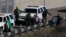 FILE - A woman and children are ushered into cars by U.S. Border Patrol agents after crossing illegally over the border wall into San Diego, Calif., as seen from Tijuana, Mexico, Dec. 9, 2018.