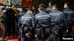 香港警察在逮捕《立场新闻》六名高管后站在该港媒办公楼外。（2021年12月19日）