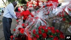 A Kenyan woman sells a bouquet of red roses to a customer for celebrations of Valentine's Day at a flower market in Nairobi, Kenya, February 14, 2012.