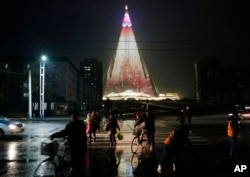 People cross a street as pyramid-shaped Ryugyong Hotel is seen in the background in Pyongyang, North Korea, Dec. 18, 2018.