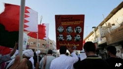 Bahraini anti-government protesters wave national flags and raise images of jailed Shiite opposition leader Sheikh Ali Salman and other protesters sentenced to death as they chant slogans demanding their freedom during a protest in Daih, Bahrain, Monday, 