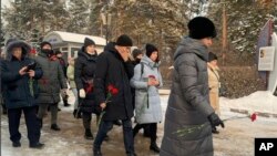 Sejumlah orang membawa bunga untuk memperingati para korban kecelakaan di tambang batu bara Listvyazhnaya di kota Siberia Kemerovo, sekitar 3.000 kilometer timur Moskow, Rusia, 26 November 2021. (Foto: AP)