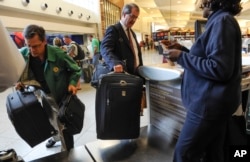 FILE - Passengers check-in their luggage at the Delta counter at Hartsfield-Jackson Atlanta International Airport, in Atlanta, Sept. 27, 2013.