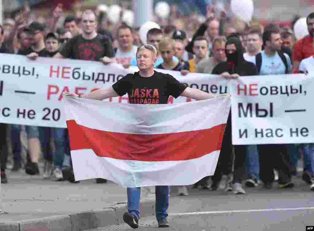 벨라루스 민스크에서 알렉산드로 루카센코 대통령의 장기집권 연장에 반대하는 시위가 계속된 가운데, 한 참가자가 옛 벨라루스 국기를 들고 걷고 있다.