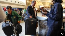 FILE - Passengers check-in their luggage at the Delta counter at Hartsfield-Jackson Atlanta International Airport, in Atlanta, Sept. 27, 2013.