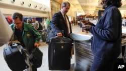 FILE - Passengers check-in their luggage at the Delta counter at Hartsfield-Jackson Atlanta International Airport, in Atlanta, Sept. 27, 2013.