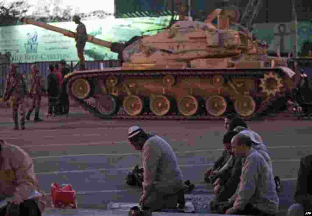 Anti-government protesters offer their evening prayers, in front of an Egyptian army tank securing the area, during a protest in Cairo's Tahrir Square, Egypt, Monday, Jan. 31, 2011. A coalition of opposition groups called for a million people to take to C