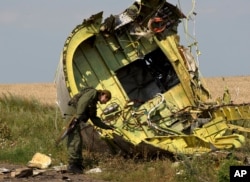 FILE - In this July 22, 2014 file photo, a pro-Russian rebel touches the MH17 wreckage at the crash site of Malaysia Airlines Flight 17, near the village of Hrabove, eastern Ukraine.