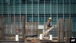 FILE - A foreign worker carries a plate on a property construction site in Kuala Lumpur, on Oct. 22, 2019.