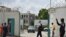 Des drapeaux français flottent en berne derrière un policier faisant un geste au départ du Premier ministre ivoirien après avoir signé un livre de condoléances à l'ambassade de France à Abidjan, le 15 juillet 2016.