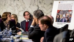 Democratic Sen. Dianne Feinstein, left, looks at a poster depicting an example of a misleading internet ad as representatives of Facebook, Twitter and Google testify during hearing on Capitol Hill in Washington, Oct. 31, 2017.