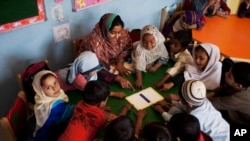 FILE - Pakistani students are seen gathered around their teacher in a classroom in Karachi, Pakistan, Feb. 24, 2014.