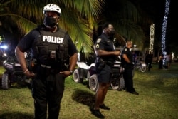 Police officers stand guard as revelers enjoy spring break festivities in Miami Beach, Florida, March 22, 2021.