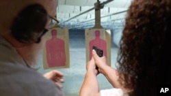 Dalam gambar yang diambil dari video pada 21 Agustus 2021 ini, Valerie Rupert sedang diberi petunjuk tentang cara yang tepat untuk menggunakan senjata api di toko Recoil Firearms di Taylor, Michigan. (Carlos Osorio/AP)