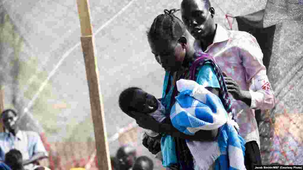A member of a Doctors Without Borders (MSF) medical team stands near a woman holding her baby on Jan. 10, 2014 at a UN compound in Juba, where thousands have sought refuge from the fighting in South Sudan. MSF medical teams are carrying out 300-500 consul
