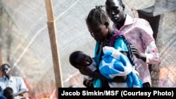 A member of a Doctors Without Borders (MSF) medical team stands near a woman holding her baby on Jan. 10, 2014 at a UN compound in Juba, where thousands have sought refuge from the fighting in South Sudan. 