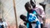 A member of a Doctors Without Borders (MSF) medical team stands near a woman holding her baby on Jan. 10, 2014 at a UN compound in Juba, where thousands have sought refuge from the fighting in South Sudan. 