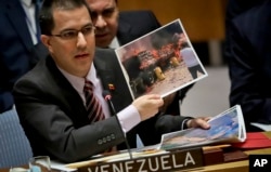 Venezuela Foreign Affairs Minister Jorge Arreaza shows pictures he said represent opposition members initiating violence during a meeting on Venezuela in the U.N. Security Council at U.N. headquarters, Tuesday Feb. 26, 2019.
