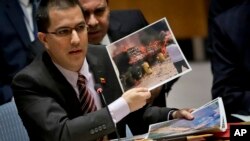 Venezuela Foreign Affairs Minister Jorge Arreaza shows pictures he said represent opposition members initiating violence during a meeting on Venezuela in the U.N. Security Council at U.N. headquarters, Feb. 26, 2019. 