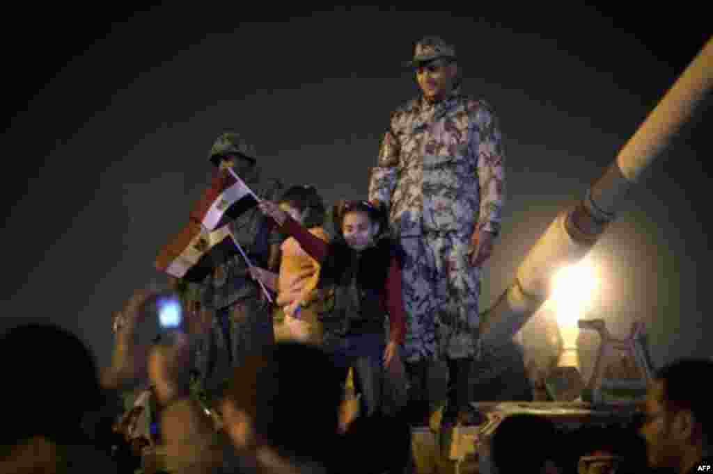 A girl poses for a photo with an Army soldier on top of a tank as anti-government protesters celebrate in Tahrir Square in downtown Cairo, Egypt , Friday, Feb. 11, 2011. Fireworks burst over Tahrir Square and Egypt exploded with joy and tears of relief a