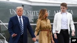 FILE - President Donald Trump, first lady Melania Trump and their son, Barron Trump, walk off of Marine One at Morristown Municipal Airport in Morristown, N.J., Aug. 16, 2020. 