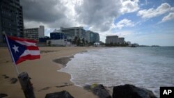 Un bandera de Puerto Rico se ve delante de una playa vacía en Ocean Park, en San Juan, Puerto Rico, el 21 de mayo de 2020. La isla está reabriendo con cautela sus negocios tras un cierre de dos meses por el coronavirus.