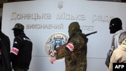 Para milisi bersenjata pro Rusia berjalan di luar kantor pemerintah di kota Donetsk (16/4). 