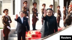 North Korean leader Kim Jong Un waves to South Korean President Moon Jae-in as they bid farewell after their summit at the truce village of Panmunjom, North Korea, May 26, 2018.