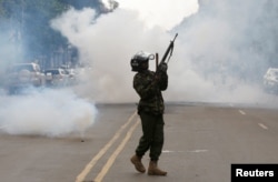 A riot policeman holds up his weapon as tear gas is fired to disperse supporters of Kenyan opposition National Super Alliance coalition, during a protest along a street in Nairobi, Kenya, Oct. 13, 2017.