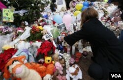 A woman puts a photo of a child on a makeshift memorial in the Sandy Hook Village of Newtown, Conn., as the town mourns victims killed in a school shooting