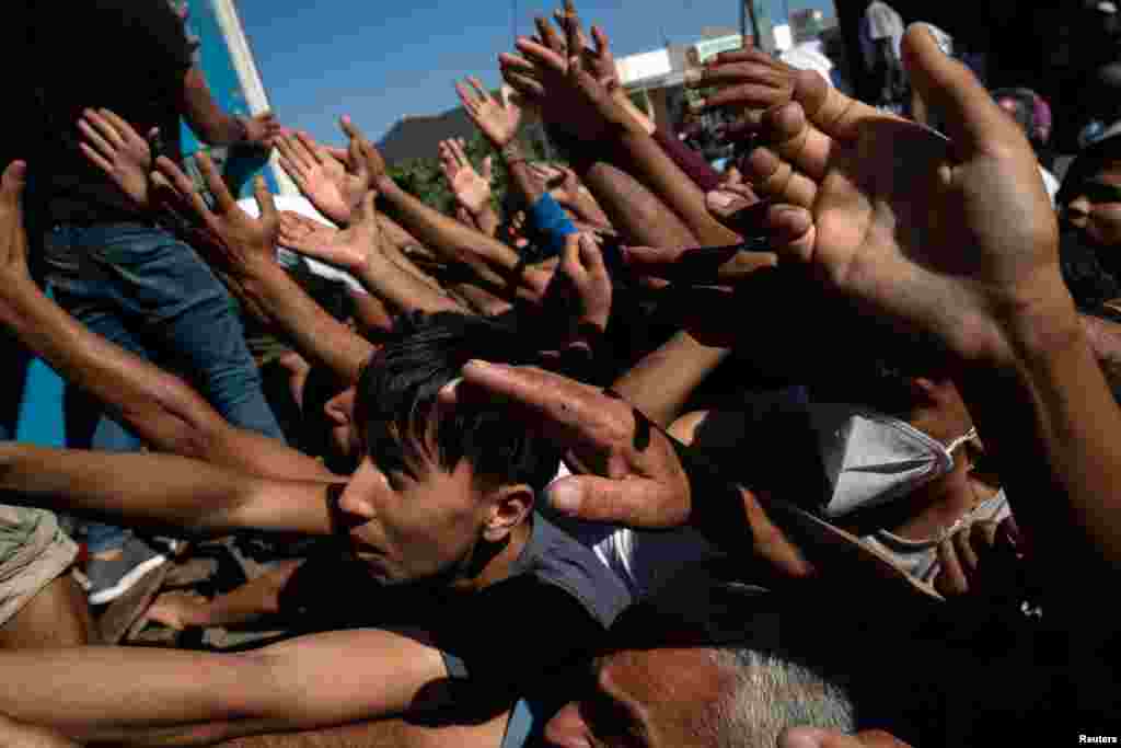 Refugees and migrants are given tomatoes during a food distribution following a fire at the Moria camp on the island of Lesbos, Greece.