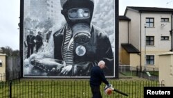 A groundskeeper uses a leaf blower in front of a mural ahead of the 50th anniversary of the 1972 "Bloody Sunday" shootings in Londonderry, Northern Ireland, Jan. 26, 2022.