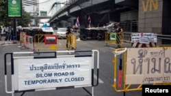 FILE - A sign indicating the closure of a main touristic road can be seen next to barricades of anti-government protesters near a main stage of the protest in Bangkok, Feb. 5, 2014. 