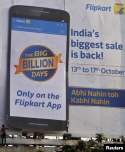 FILE - A worker removes an advertisement billboard of Indian online marketplace Flipkart, installed along the roadside in Mumbai, India, Oct. 16, 2015. Amazon.com Inc. is concentrating on India and its competition, Flipkart.
