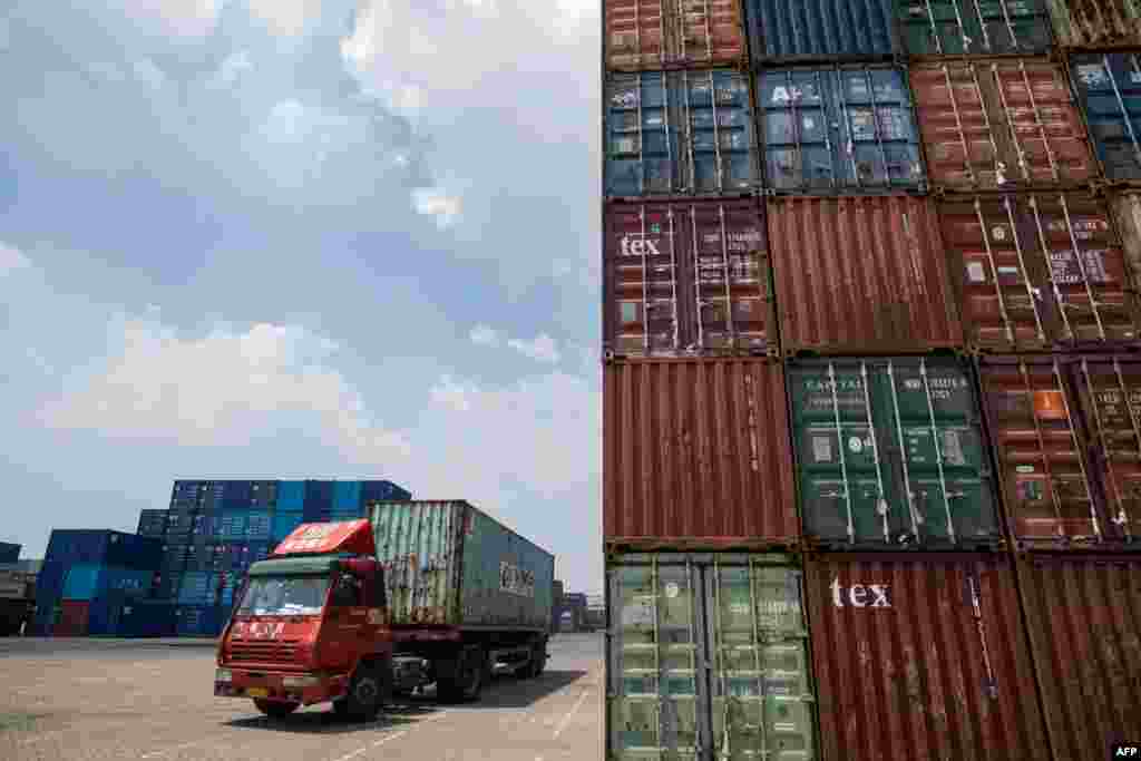 2018年8月7日，中国江苏省张家港港口堆放着集装箱，一辆卡车运输集装箱，在旁边开过。