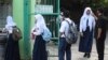 Petugas keamanan memeriksa suhu tubuh para siswa sebelum mereka memasuki halaman sekolah mereka di Bekasi, pinggiran Jakarta, 13 Juli 2020. (Foto: dok)