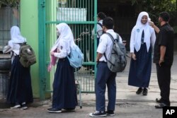 Seorang penjaga keamanan memeriksa suhu tubuh seorang siswa sebelum memasuki sekolahnya pada 13 Juli 2020. (Foto: AP/ACHMAD Ibrahim)