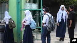 Petugas keamanan memeriksa suhu tubuh para siswa sebelum mereka memasuki halaman sekolah mereka di Bekasi, pinggiran Jakarta, 13 Juli 2020. (Foto: dok)