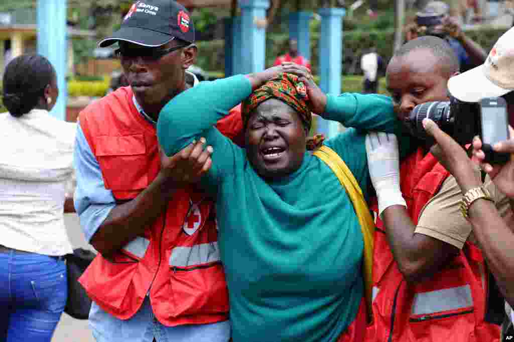 Kenya Red Cross staff assist a woman after she viewed the body of a relative killed in Thursday's attack on a university, at Chiromo funeral home, Nairobi, Kenya, April 3, 2015.