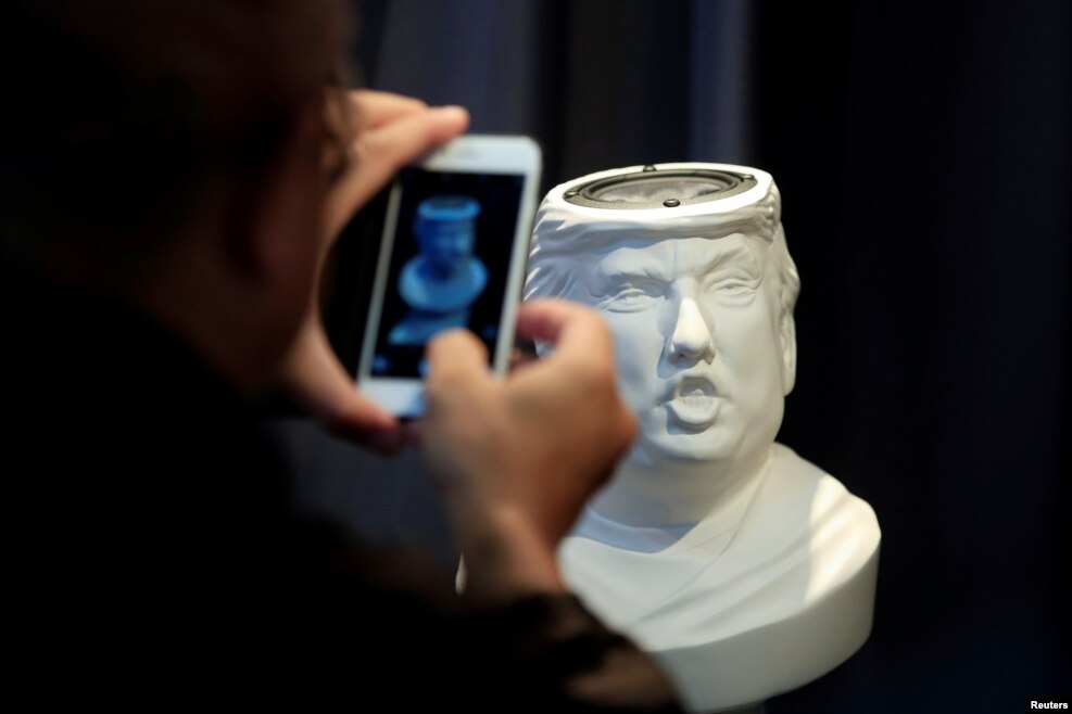 A man takes picture of a Sound Of Power speaker in the shape of a bust of Donald Trump is displayed at the CES (Consumer Electronics Show) Asia 2016 in Shanghai, China.