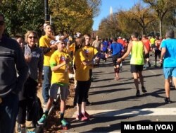 FILE - Teens wearing cow-horn hats and ringing cow bells cheer on runners in the Marine Corps Marathon along Independence Avenue in Washington in October 2014.