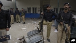 Pakistani police officers stand guard at the office of local electrical company attacked by angry protesters to condemn electricity shortages in Lahore, March 2012. 