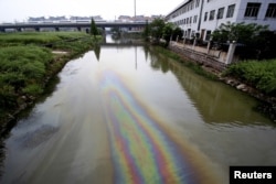 FILE - A China Railway High-speed (CRH) Harmony bullet train travels above a river contaminated by leaked fuel, in Shaoxing, Zhejiang province, China on April 29, 2015.