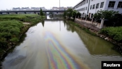 FILE - A Chinese bullet train travels above a river polluted by leaked fuel, in Shaoxing, Zhejiang province, China, April 29, 2015.