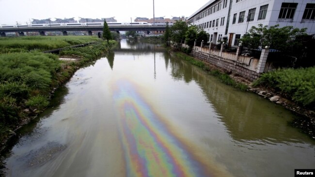 FILE - A Chinese bullet train travels above a river polluted by leaked fuel, in Shaoxing, Zhejiang province, China, April 29, 2015.