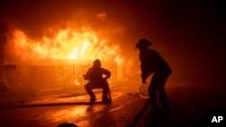 Firefighters try to save a home on Tigertail Road during the Getty fire, Monday, Oct. 28, 2019, in Los Angeles, Calif. (AP Photo/ Christian Monterrosa)