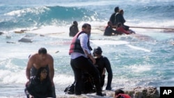 A man rescues an migrant from the Aegean sea, in the eastern island of Rhodes, April 20, 2015.